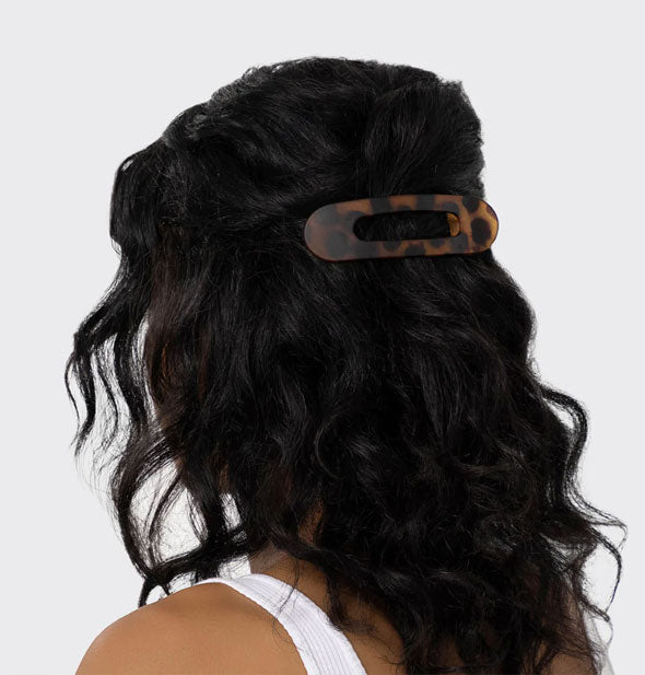 Model wears a brown tortoise hair clip with slotted design in a half-up style