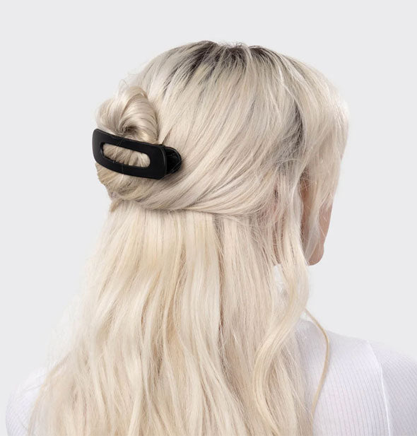 Model wears a matte black hair clip with slotted design in a twisted half-up style