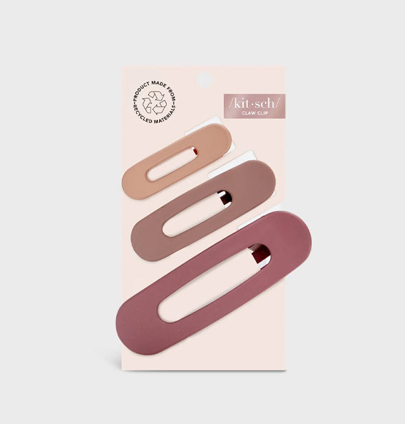 Three slotted hair clips in warm, earthy tones in matte finishes are secured to a light pink Kitsch product card