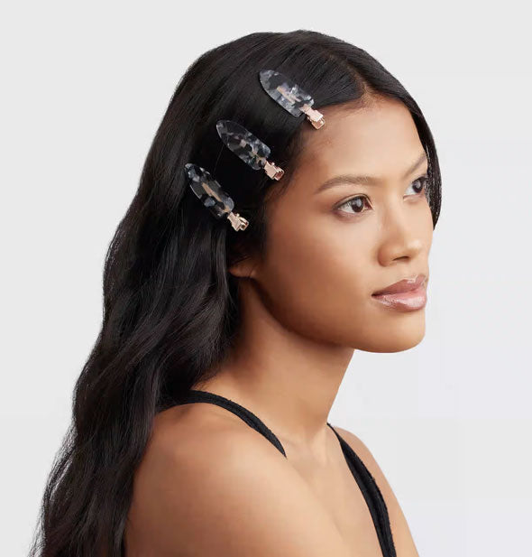 Model wears three terrazzo-effect clips in a front section of hair