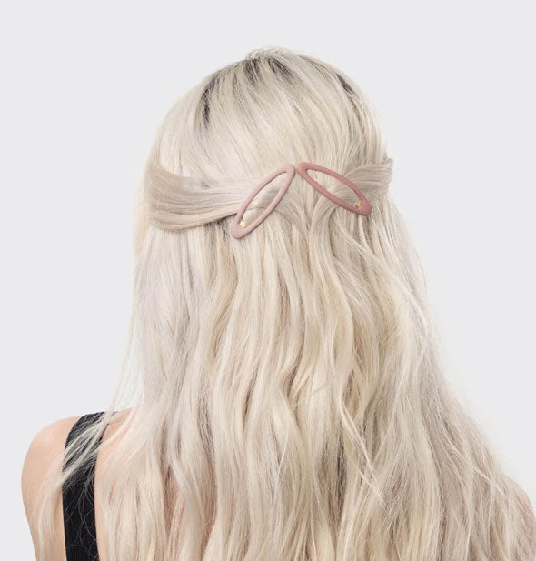 Model wears two light-colored matte open shape clips side-by-side and angled outward in two piecey pulled-back strands