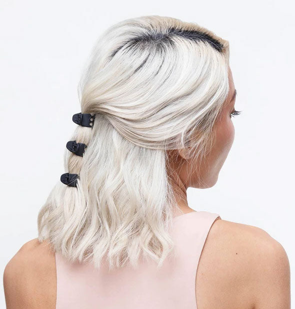 A model wears three mini black claw clips in a part-up/part-down style