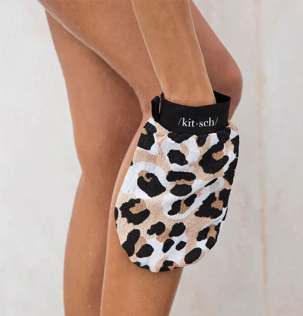 Model uses Kitsch's exfoliating leopard print bath mitt on lower leg