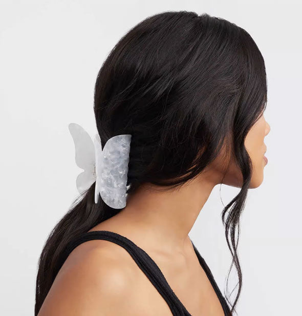 Model wears a white butterfly claw clip in a low ponytail