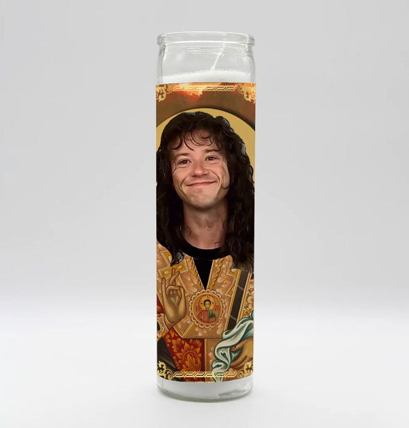 Tall white prayer candle in clear glass with all-over artwork depicting the character Eddie from Stranger Things as a saint