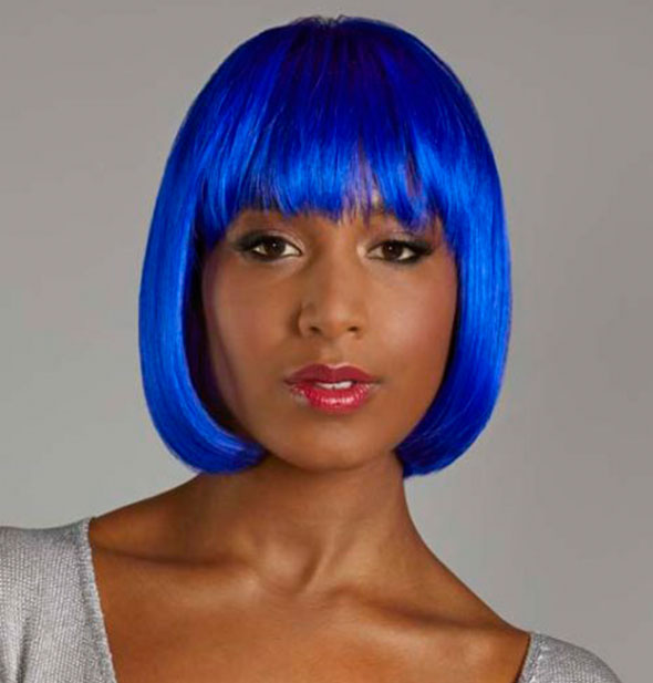 Model wearing a short, bright blue wig with bangs.