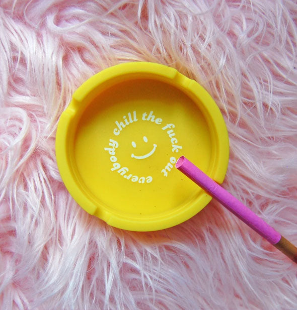 Round yellow ashtray with white printing in the bottom that says, "Everybody chill the fuck out" encircling a smiley face