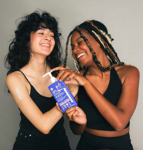 Two smiling models with a bottle of Somebody Everyday Nourishing Body Lotion; one model has a small smear of lotion on upper arm
