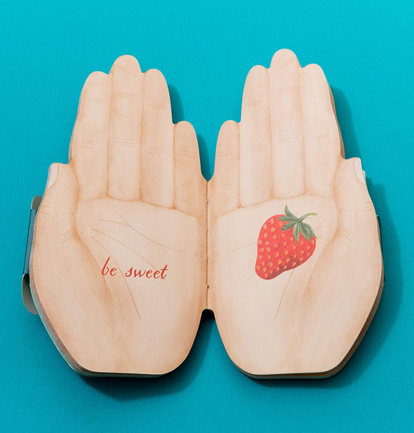 Open hands book is open to a page spread with strawberry and the words, "Be sweet"