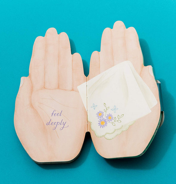 Open hands book is open to a page spread with embroidered handkerchief design and the words, "Feel deeply"