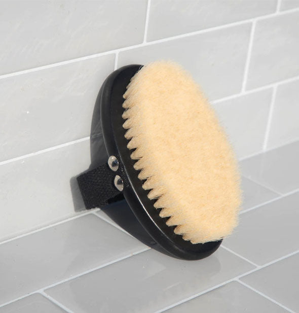 Black body brush with natural bristles sits propped against a tiled surface