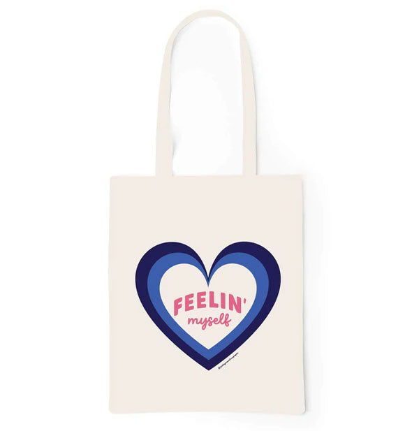 White tote bag with two-tone blue heart graphic inside of which pink text reads, "Feelin' myself"