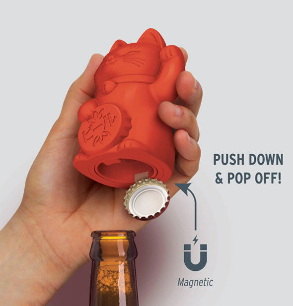 Model's hand demonstrates removal of a bottle cap with the Feline Lucky Bottle Opener; labeled with infographic is its magnetic feature and, "Push down & pop off!"
