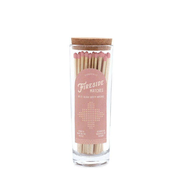 Clear glass bottle with cork lid is filled with pink-tipped wooden matches and features a stylized pink label