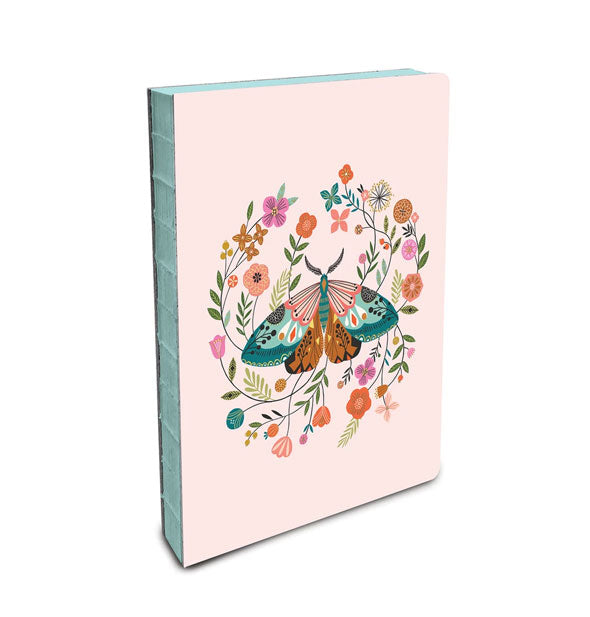 Blush pink notebook with colorful moth and flowers design features an exposed teal binding and page edges
