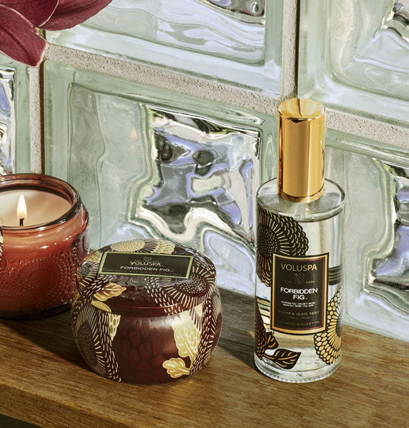 Voluspa Forbidden Fig candles and spray sit on a wooden shelf