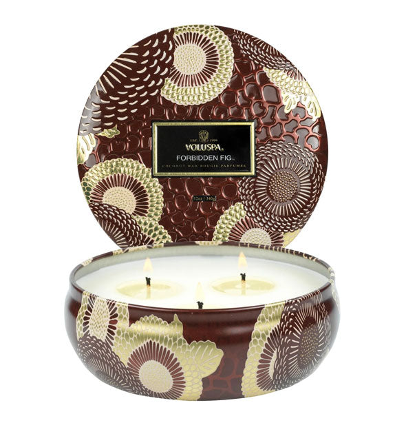 Decorative embossed tin Forbidden Fig Voluspa candle with three lit wicks