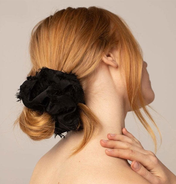 Model wears a frayed black hair scrunchie in a low bun