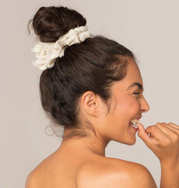 Smiling model wears a frayed white hair scrunchie in a topknot