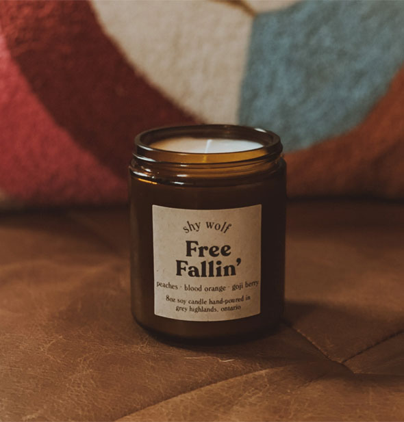 8 ounce Free Fallin' candle by Shy Wolf in amber glass jar on a leather cushion