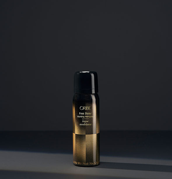Small black and gold can of Oribe Free Styler Working Hairspray on dark gray background