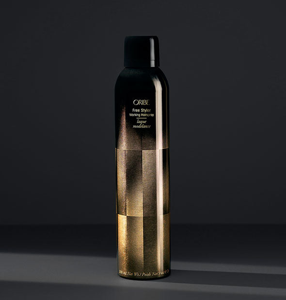 Black and gold can of Oribe Free Styler Working Hairspray on dark gray background