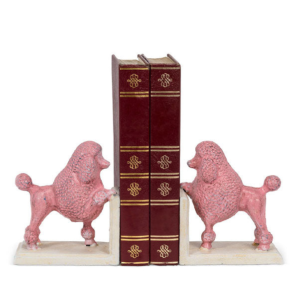 Painted cast iron pink poodle bookends on white L-shaped bases hold together a vertical stack of two books