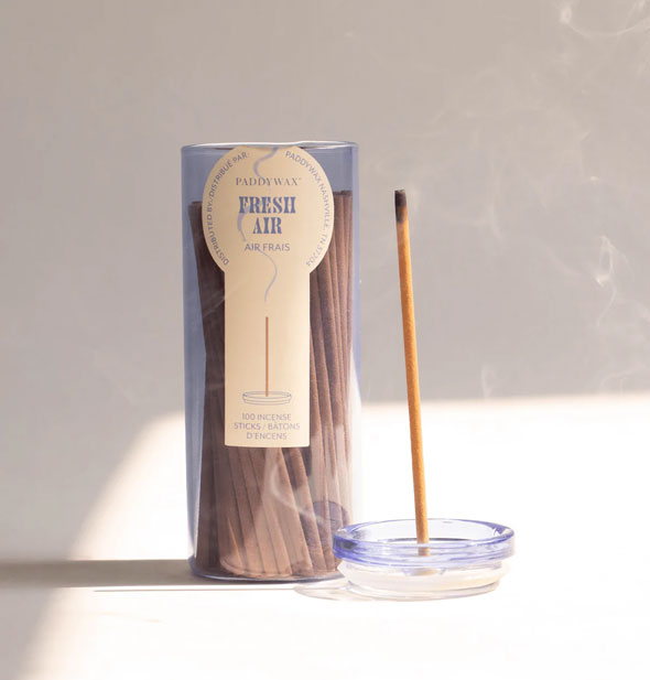 Lid removed from a glass tube of Paddywax Fresh Air incense sticks doubles as a holder for one burning stick