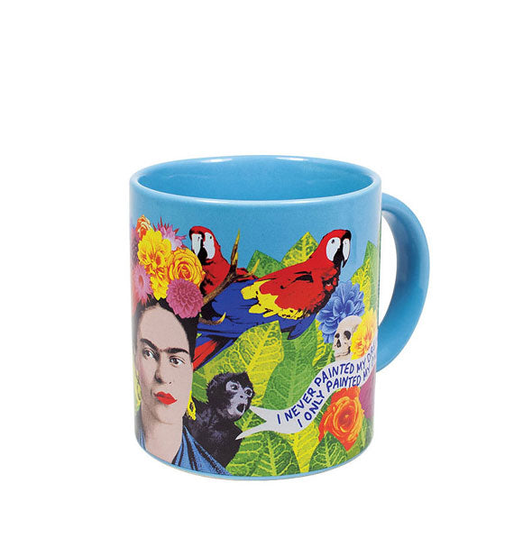 Blue coffee mug with portrait of artist Frida Kahlo and colorful all-over flowers, leaves, parrots, a monkey, and skull next to her quote in a white banner