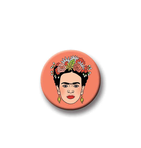 Round coral-colored magnet with portrait of artist Frida Kahlo in floral headpiece