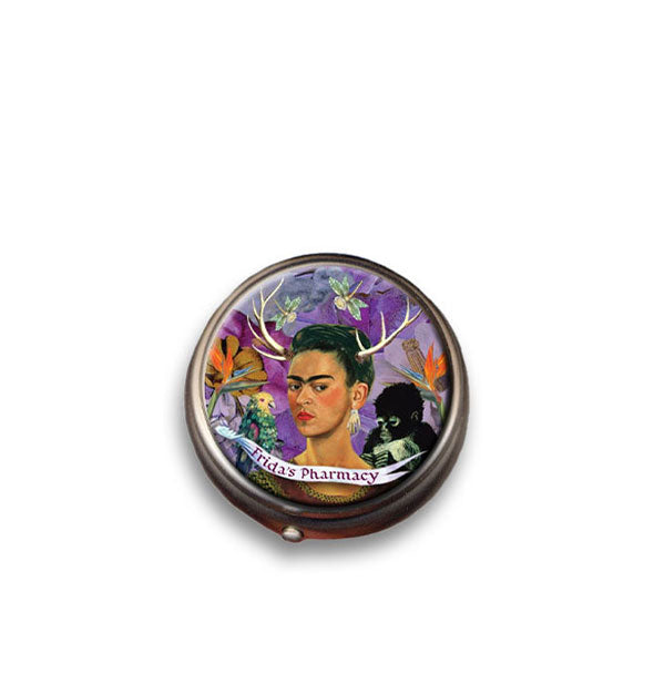 Round pill case with portrait of Frida Kahlo with deer antlers under which is a banner that says, "Frida's Pharmacy"