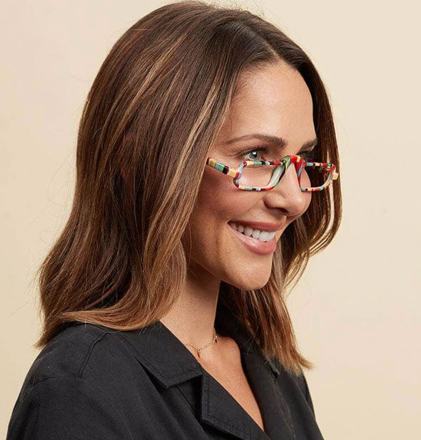 Smiling model wears a colorful pair of striped reading glasses with a raised nose bridge