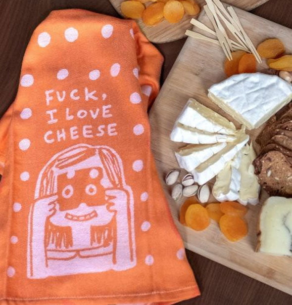 Orange illustrated Fuck, I Love Cheese towel lays alongside a charcuterie board