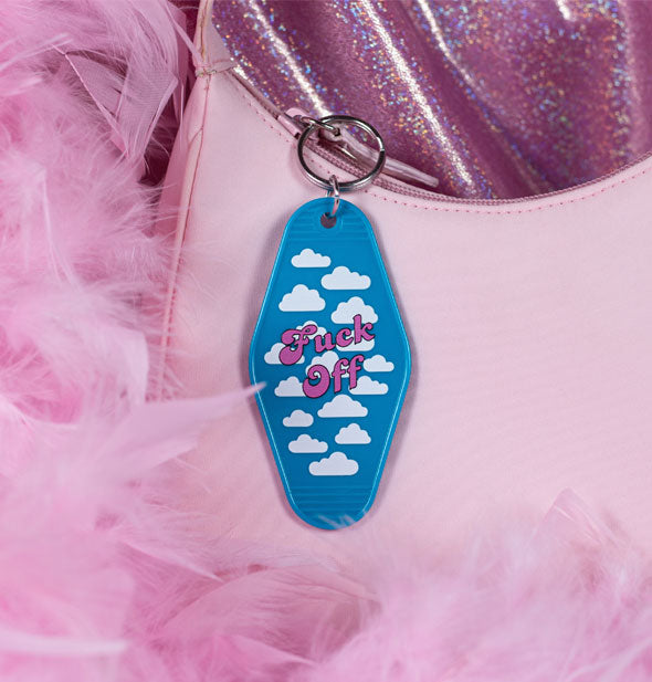 Blue motel-style keychain tab with white cloud pattern says, "Fuck Off" in pinklettering