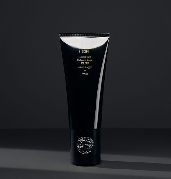 Black bottle of Oribe Gel Sérum for Radiance, Magic and Hold on dark gray background