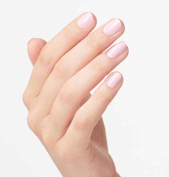 Model's hand wears a shade of soft, light pink nail polish