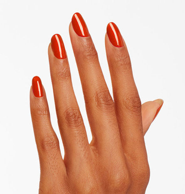 Model's hand wears a shimmery red shade of nail polish