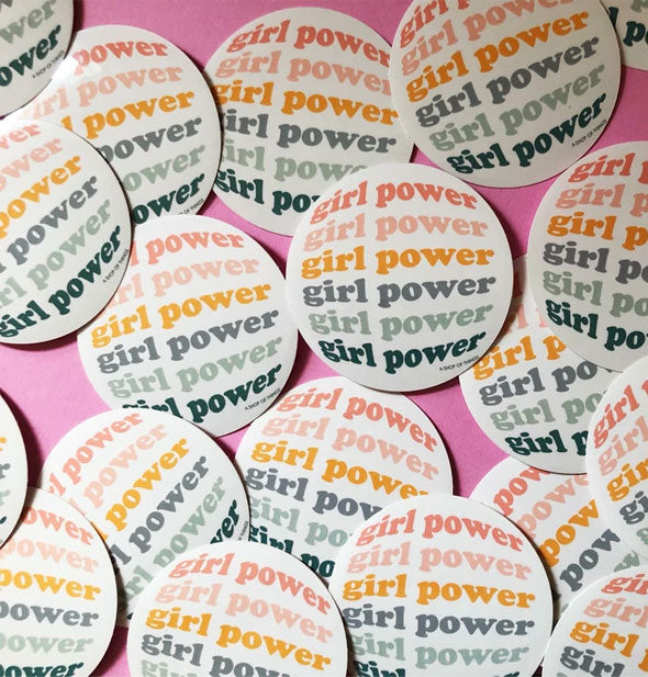 An arrangement of round Girl Power stickers on pink background