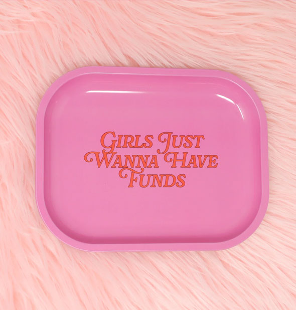 Rounded rectangular pink tray resting on a pink fur surface says, "Girls just wanna have funds" in orange lettering