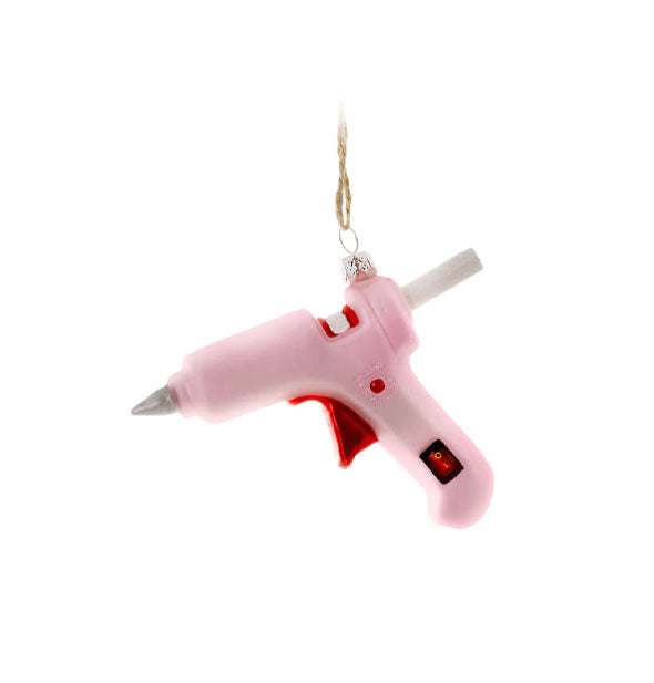 Hanging ornament is painted and designed to resemble a pink glue gun with glue stick hanging partially out the back