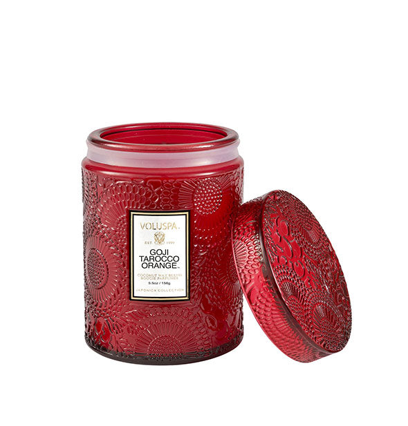 Petite red embossed glass jar candle with lid set to the side