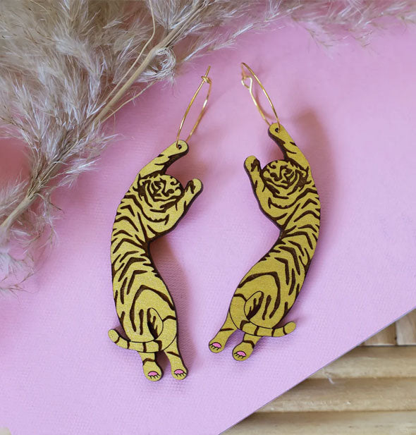 Pair of gold Tiger Hoop Earrings on pink surface