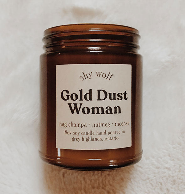 Amber glass jar Gold Dust Woman candle on white fur background