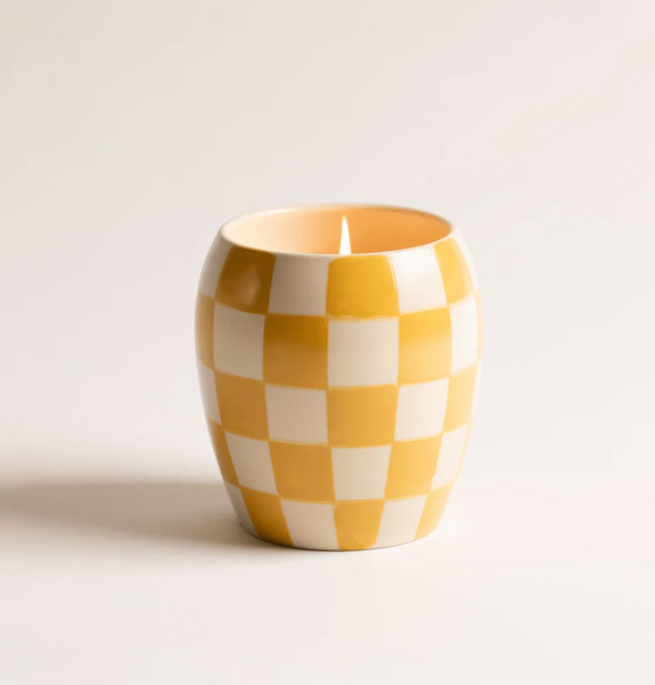 Lit white and yellow checkered candle vase