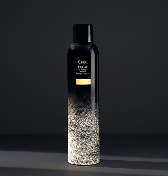 Black and gold can of Oribe Gold Lust Dry Shampoo on dark gray background