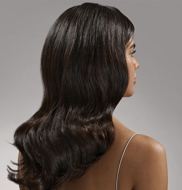Model with long, straight hair demonstrates the result of using Oribe Gold Lust Nourishing Hair Oil