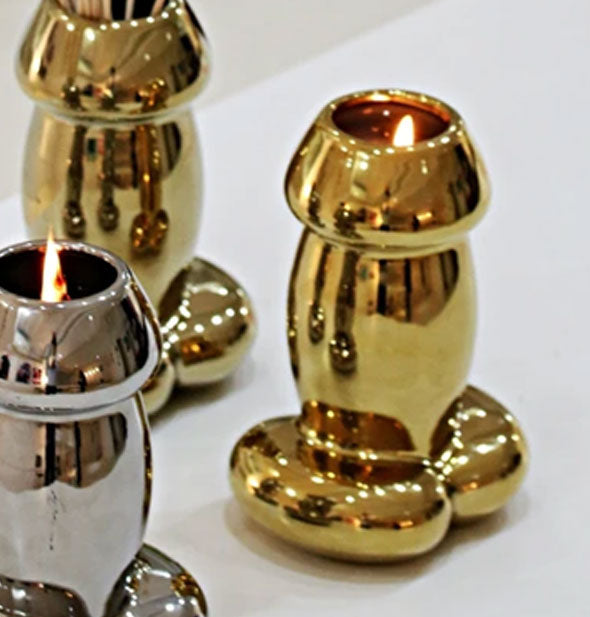 Shiny metallic penis-shaped candles on a white countertop