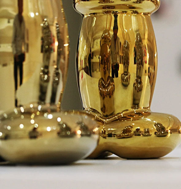 Shiny gold penis-shaped candles on a white countertop