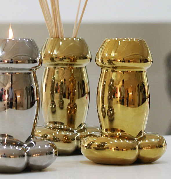 Shiny metallic penis-shaped candles and diffuser on white countertop