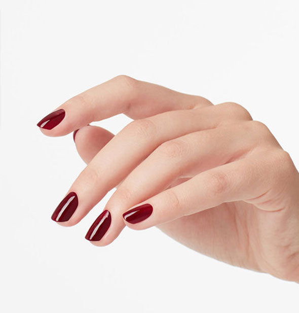 Model's hand wears a dark red shade of nail polish